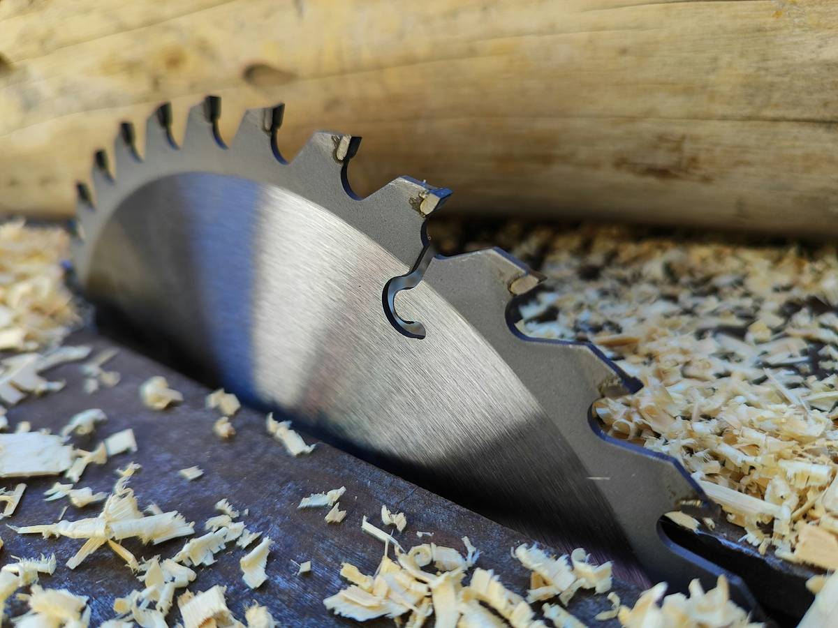 Close-up of multi material circular saw blade cutting through layered composite board