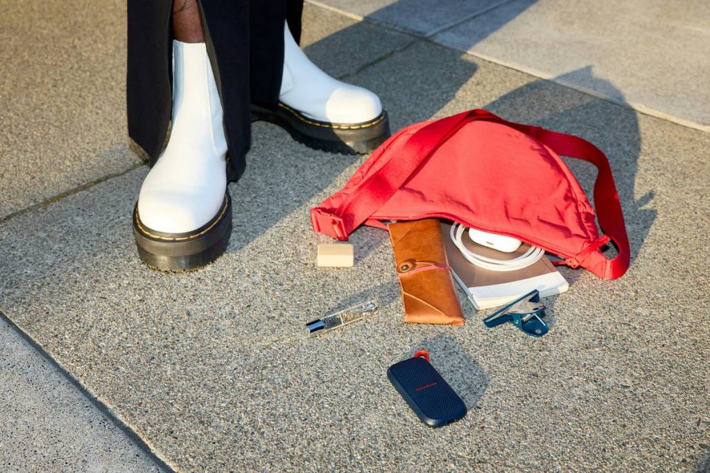 Spilled red bag contents next to white boots on concrete.